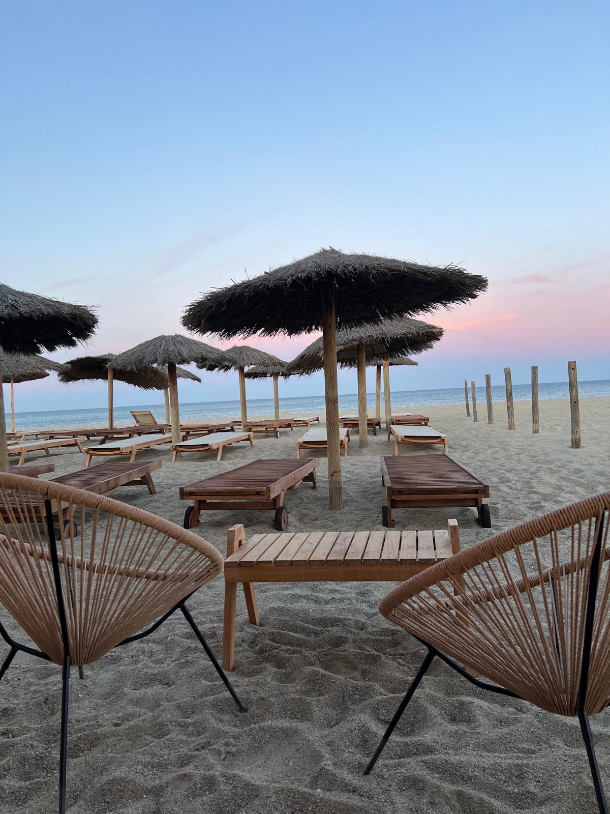 Transats et parasols en paille au coucher du soleil